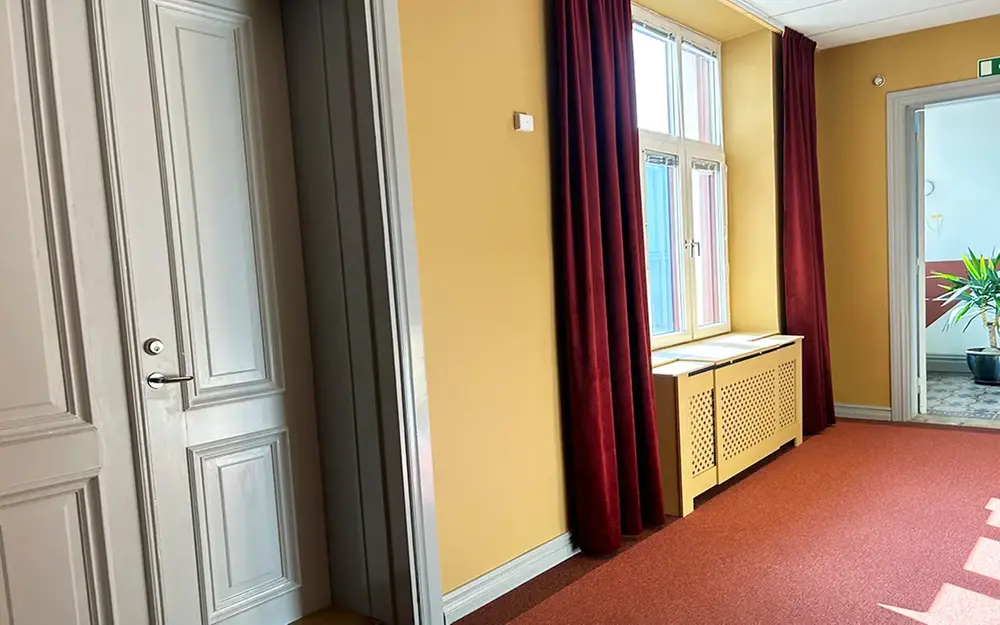 Rum med gula väggar, grå dörr och röda gardiner
