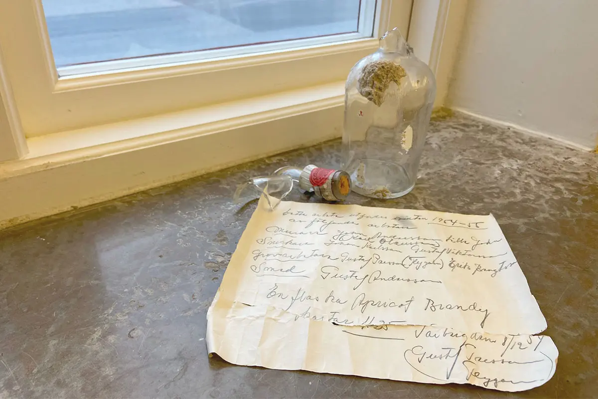 En trasig gammal flaska står i ett fönster. Ett handskrivet brev från 1954 ligger framför flaskan.