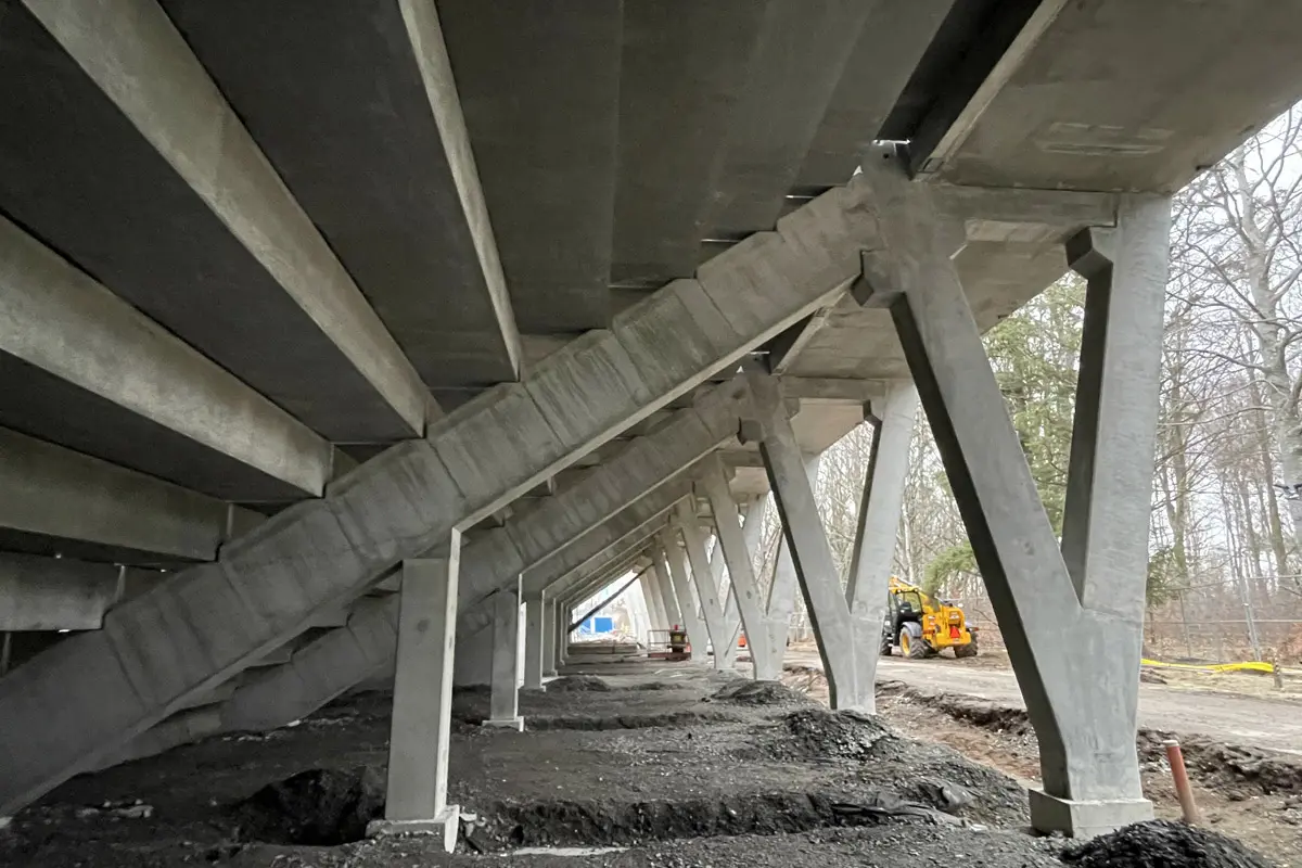 Undersidan av läktaren i betong där de olika sektionerna bildar en trappliknande struktur. Jättelika pelare i betong håller uppe konstruktionen.