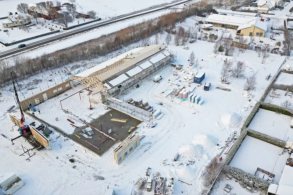 Ett drönarfot över byggarbetsplatsen som är täckt av snö. Formen på förskolan syns.