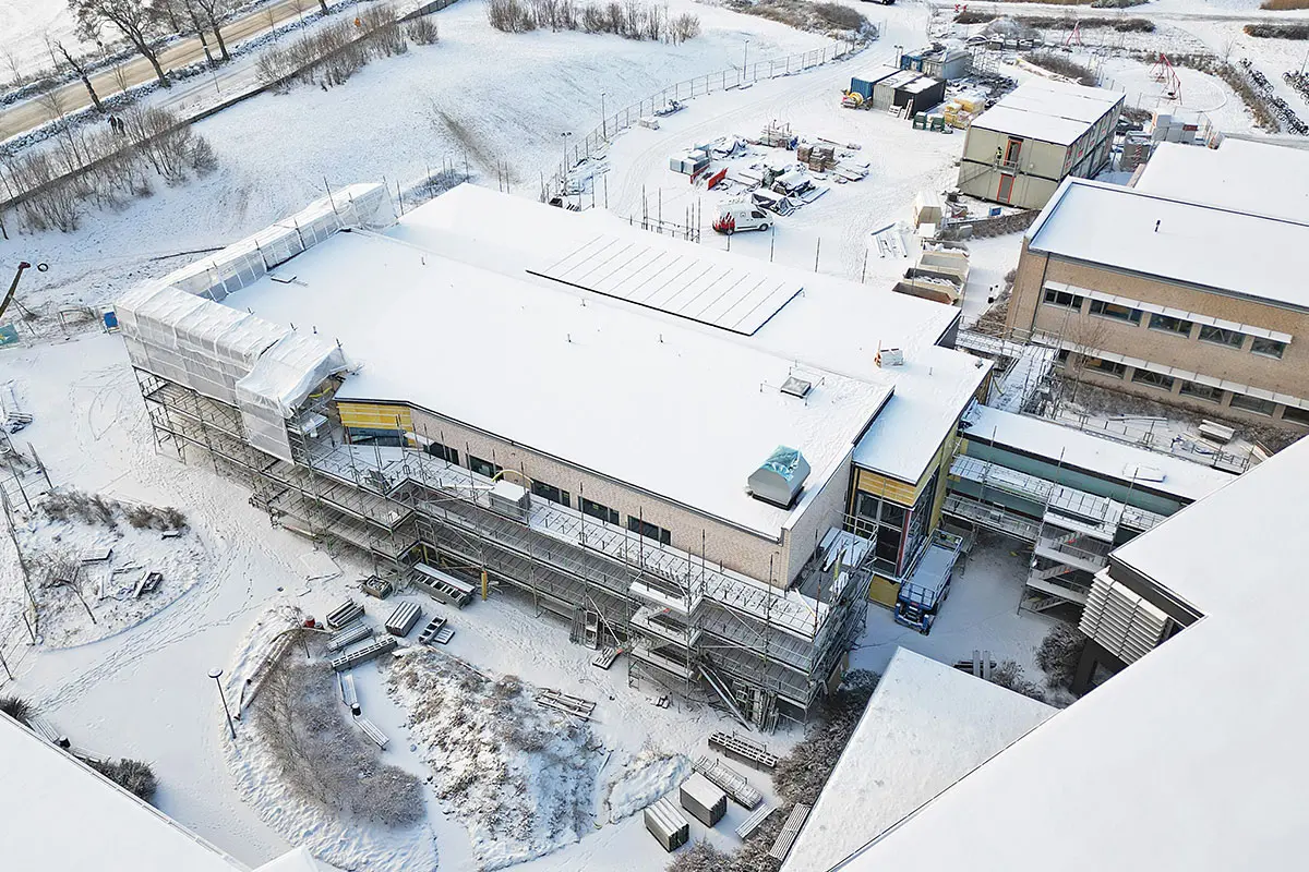Vintrig drönarbild över tillbyggnaden på Trönningeskola. Hela vyn täcks av ett tunt snötäcke.
